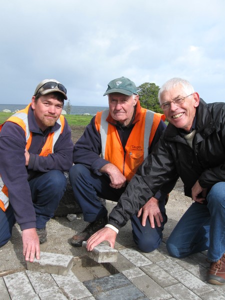 TDC staff members Aaron Brunton and Ray Dunlop with Councillor Barry Hickling laying the final pavers of the Great Lake Walkway.   